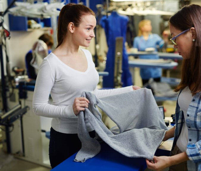 Owner of clothing restore workshop showing her client pullover